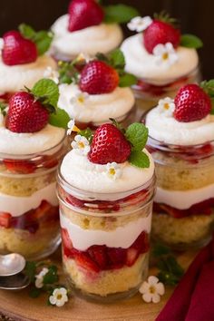 strawberry shortcakes in jars with whipped cream and fresh strawberries on the top