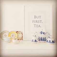 a white shelf topped with blue and white teapots next to a framed photograph