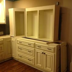 an empty kitchen with white cabinets and wood flooring in the middle of the room