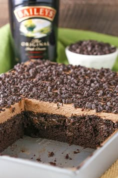 a chocolate cake with one slice missing from it and a bottle of beer in the background