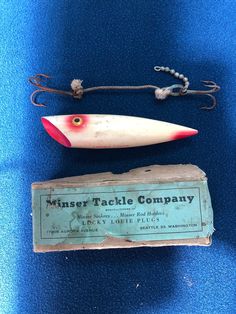 an old fishing lure next to a box on a blue surface