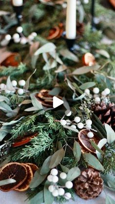 the table is decorated with greenery and pine cones, candles, and other decorations