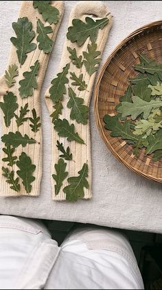 some green leaves are on the table next to a plate and napkins that have been placed on it