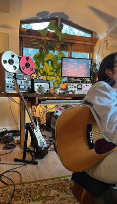 a man sitting in front of a computer holding a guitar