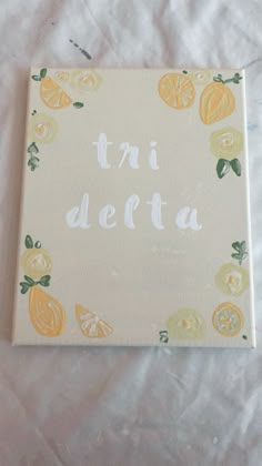 a canvas with the words tri deita written in white paint surrounded by lemons and oranges