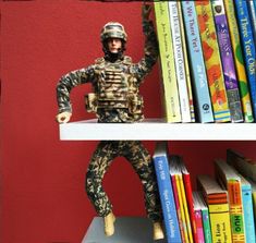 a toy soldier standing on top of a book shelf next to a bookshelf