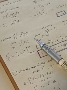 a pen sitting on top of a piece of paper with calculations written all over it