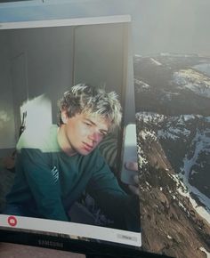 a man sitting on top of a laptop computer next to a snow covered mountain range