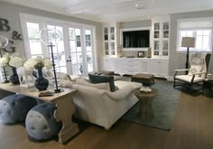 a living room filled with white furniture and lots of windows on either side of the wall