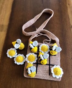 a crocheted bag with flowers on it sitting on top of a wooden table