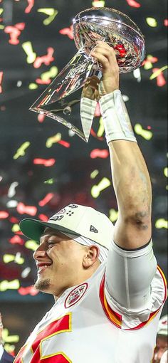 a man holding up a trophy in front of confetti