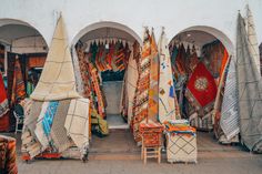 an outdoor market with lots of different colored rugs and blankets on display for sale