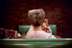 the back of a woman's head as she sits in a booth