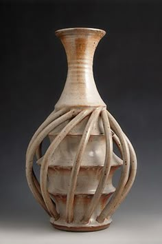 a white vase sitting on top of a table next to a gray wall and floor