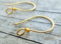 gold earrings on wooden surface with wire wrapped around the ear and looped at the end