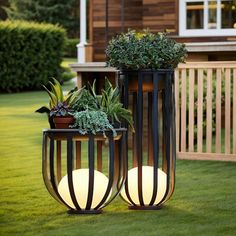 two planters with plants in them sitting on the grass near a deck and house