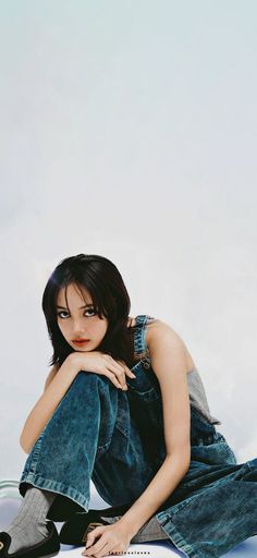 a young woman sitting on the ground with her legs crossed and looking at the camera