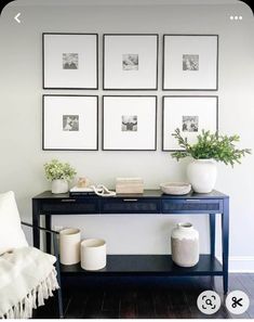 a black table with white vases and pictures on the wall in front of it