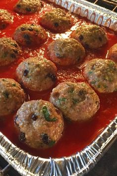 some meatballs are sitting on top of sauce in a baking pan, ready to be cooked