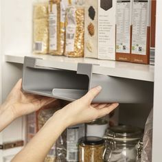 a person reaching for something on the shelf in a pantry with other food items behind them