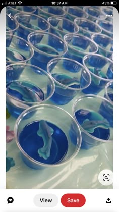 several cups filled with blue liquid sitting on top of a white table covered in plastic containers