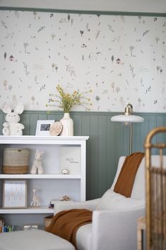 a baby's room is decorated in white and green with flowers on the wall