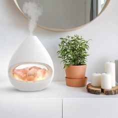 an air humider sitting on top of a white counter next to a potted plant