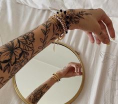 a woman's arm with tattoos on it and a mirror in the foreground