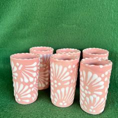 four pink vases with white designs on them