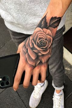 a man's hand with a rose tattoo on it and a bird in the middle