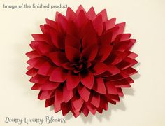 a large red paper flower on a white wall with the words, image of the finished product