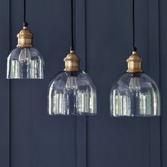 three clear glass pendant lights hanging from a ceiling