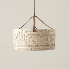 a light fixture hanging from a ceiling with wood strips on the bottom and brown leather cord