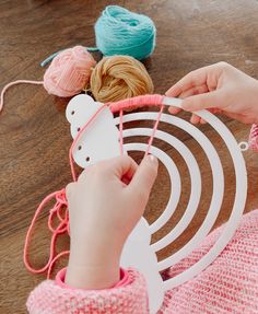 a person is knitting yarn on top of a wooden table with crochet hooks