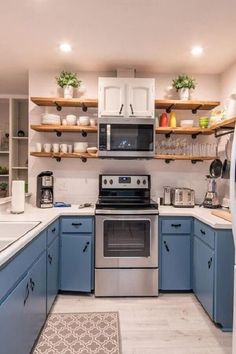 a kitchen with blue cabinets and stainless steel stove top oven, white counter tops and open shelving