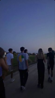 a group of people walking down a road at dusk