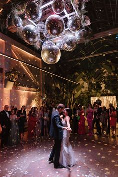 a bride and groom are dancing on the dance floor at their wedding reception with bubbles floating from the ceiling