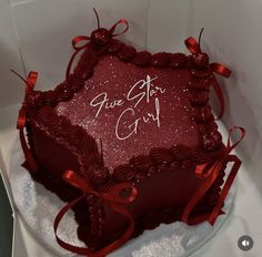 a heart shaped cake sitting on top of a white plate with red ribbon around it