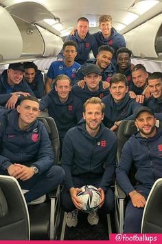 a group of men sitting on top of an airplane with soccer balls in their hands