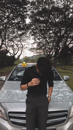 a man standing in front of a car with an emoticive smiley face on his forehead