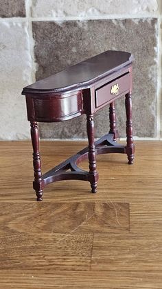 a small wooden table sitting on top of a hard wood floor next to a brick wall