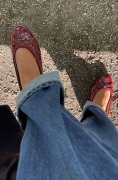 a woman's feet in jeans and red shoes