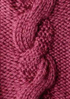 close up view of the texture of a knitted sweater in dark pink, with a knot at the end