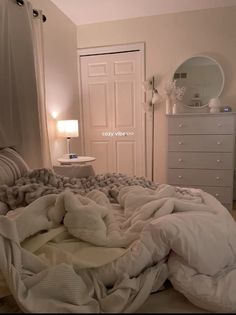 an unmade bed with blankets and pillows on top of it in a white bedroom