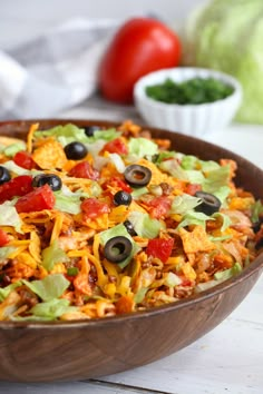 a wooden bowl filled with taco salad and olives