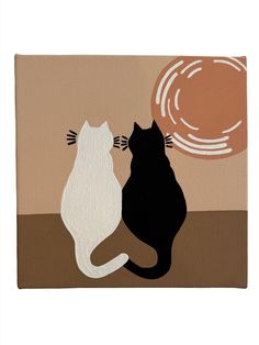 two black and white cats sitting next to each other in front of a brown background