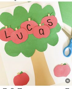 an apple tree cut out with the word lucas on it and scissors next to it