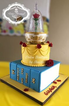 a beauty and the beast themed cake on top of a stack of books with roses