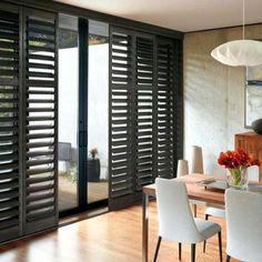 a dining room table with chairs and a vase on top of it next to sliding glass doors