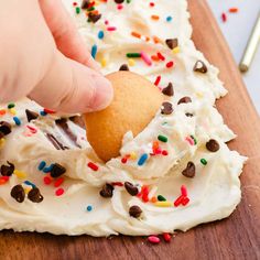 someone is dipping a cookie into some white frosting with sprinkles on it